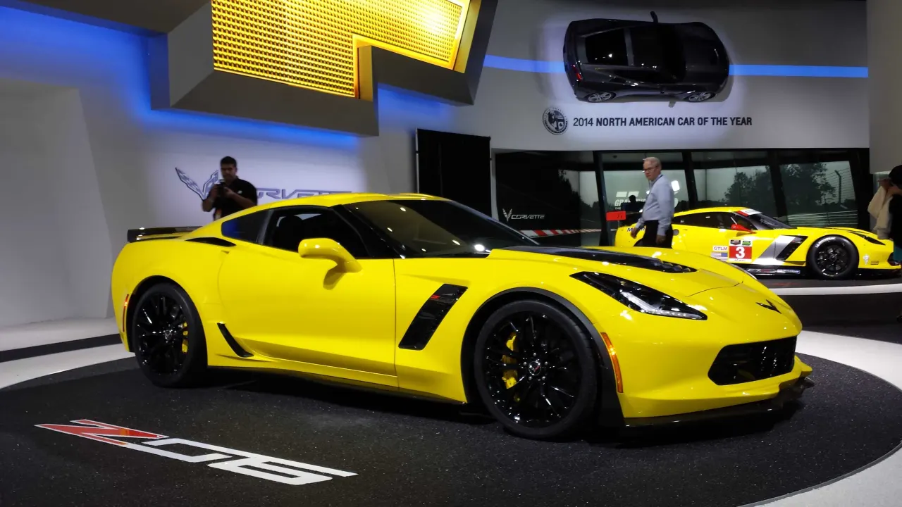 A yellow Chevrolet Corvette on a motor show stand