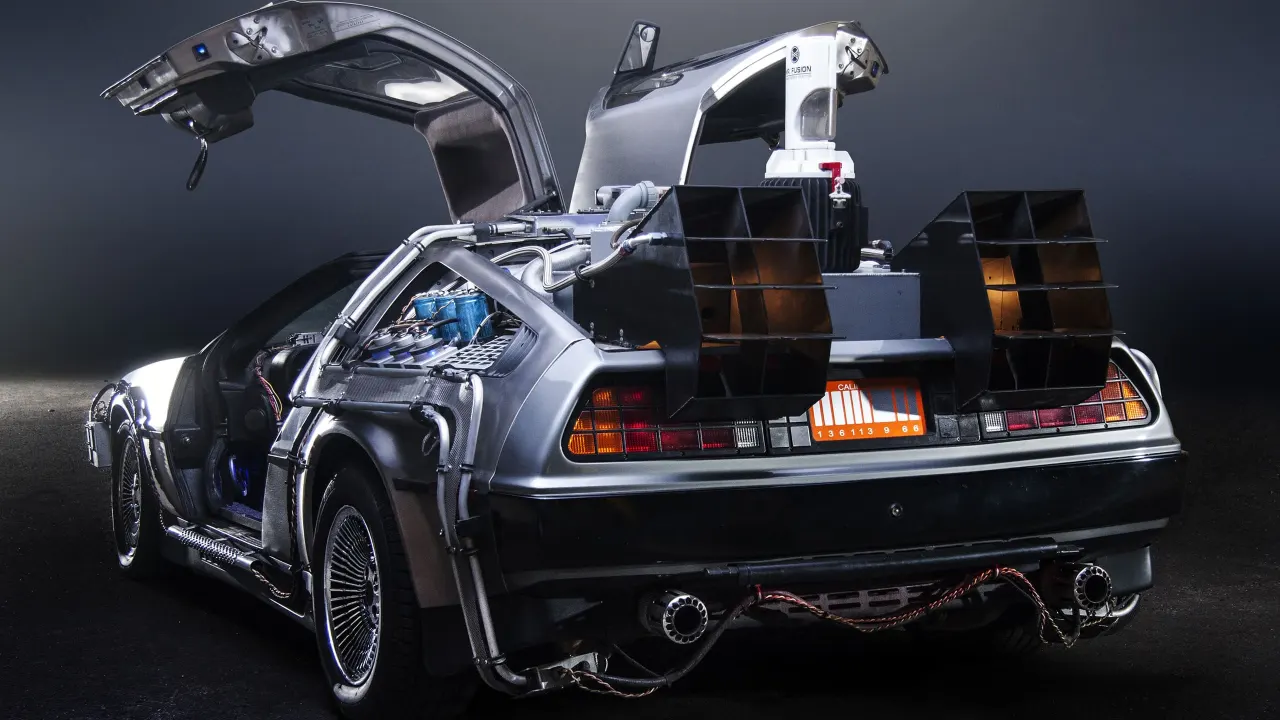 A DeLorean with its gullwing doors open and equipment loaded in the back