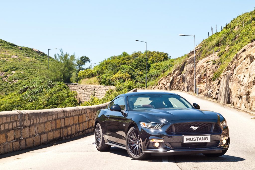 Car driving along a road surrounded by cliffs and greenery