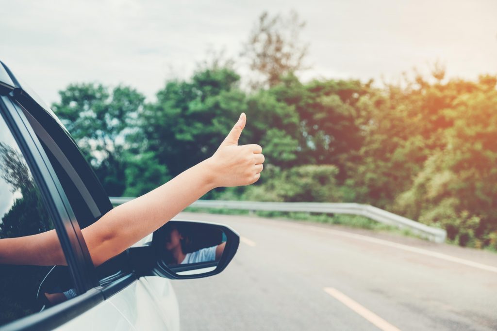 Woman with thumb sticking out of car