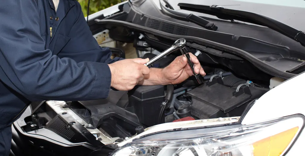 Car mechanic examining ECM unit to address electrical faults.