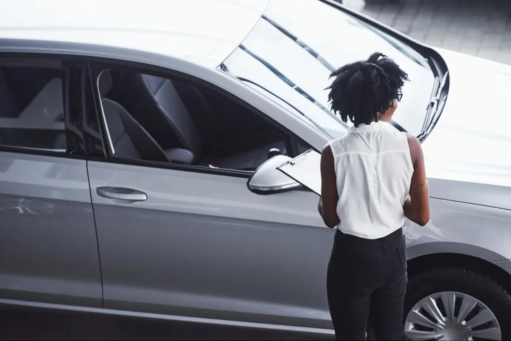Female auto technician with clipboard examines a vehicle, highlighting inspection steps and PCM replacement cost evaluation.