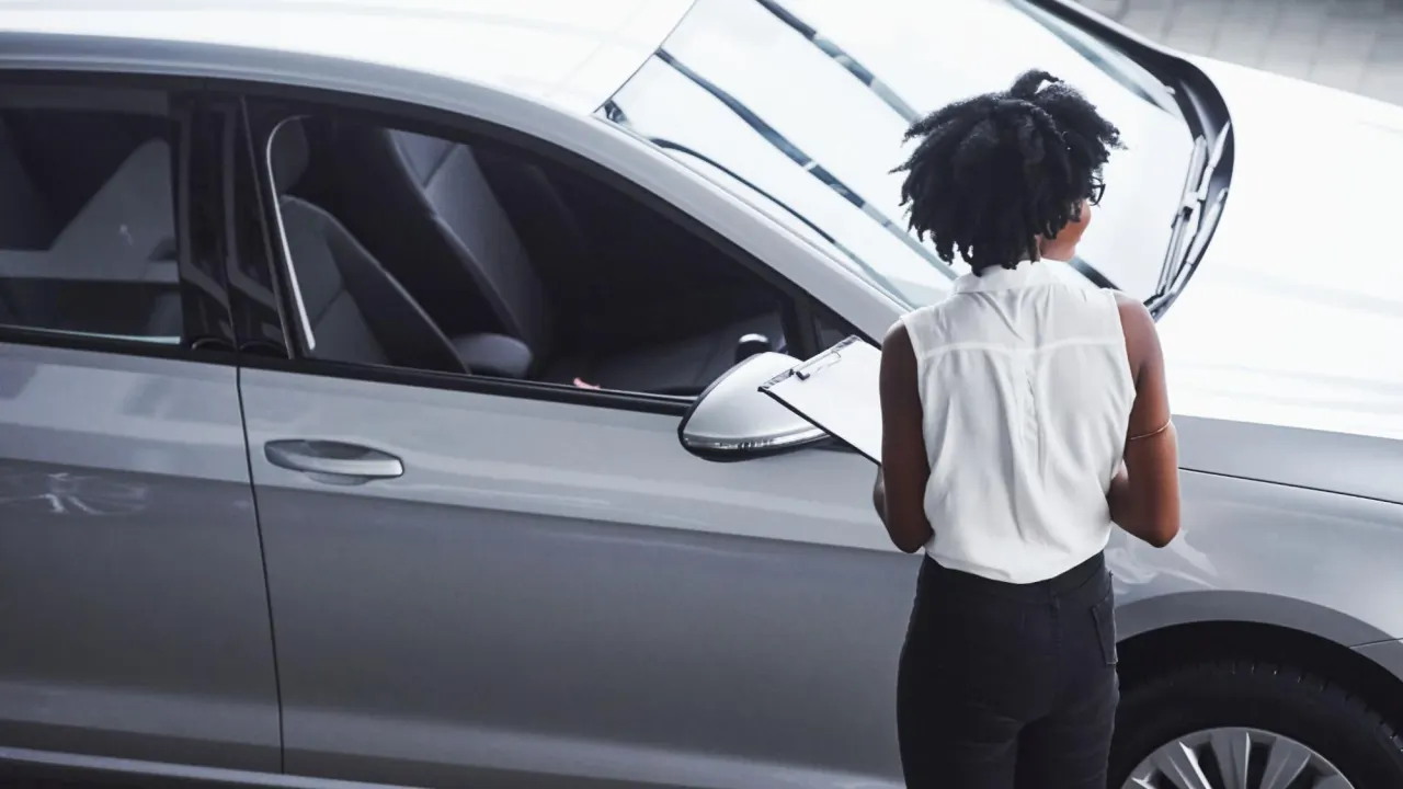 Female auto technician with clipboard examines a vehicle, highlighting inspection steps and PCM replacement cost evaluation.