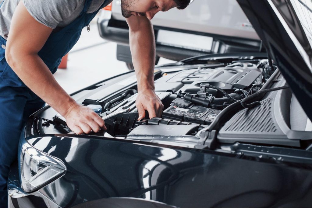 Automotive technician inspecting engine components during PCM car diagnostics