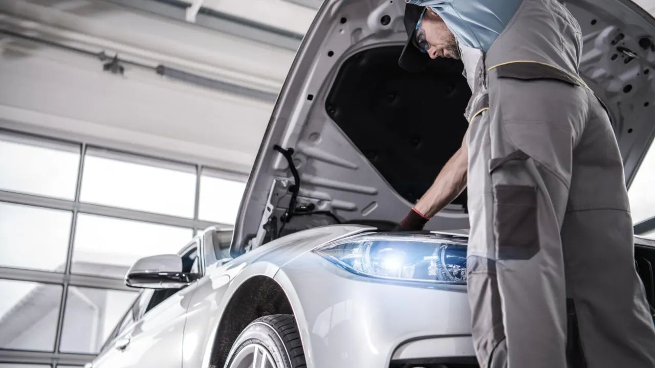 Certified auto mechanic inspecting a modern vehicle’s engine for PCM diagnostics inside a professional car service garage