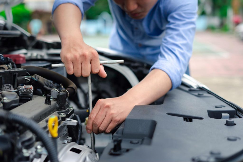 Frustrated car owner examining engine bay on roadside due to OBD showing power but no communication.