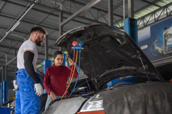 Auto technician and client reviewing diagnostics under the hood as part of a comprehensive BCM repair service in a professional garage