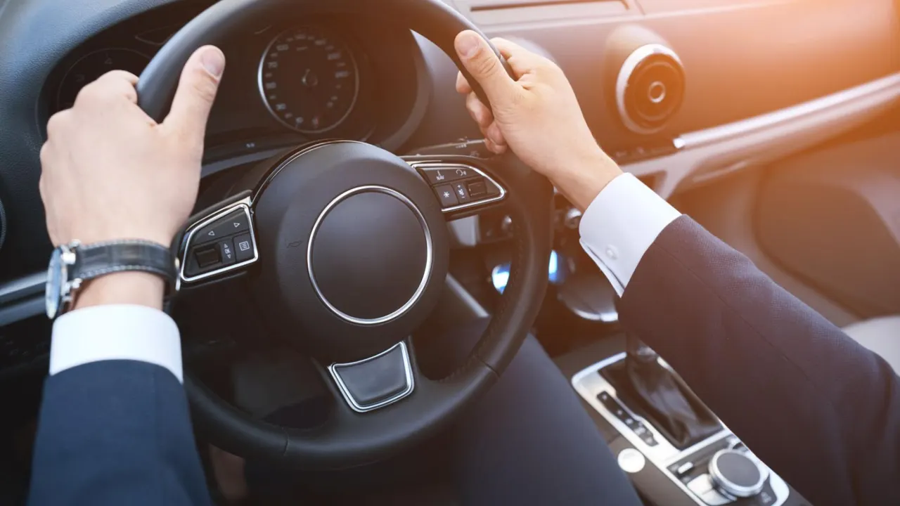 Business driver holding a steering wheel inside a car, related to where is the ecm located.