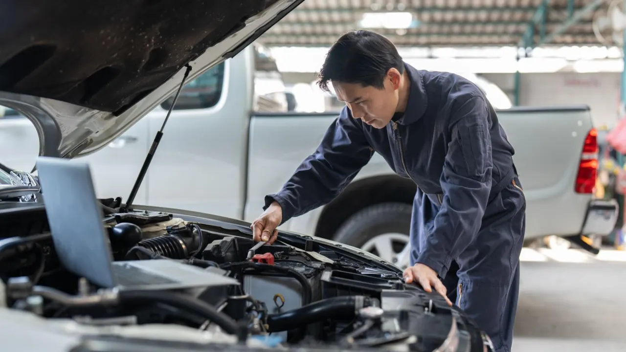 Professional mechanic cleaning and examining a vehicle’s engine area during Car BCM inspection and diagnostics