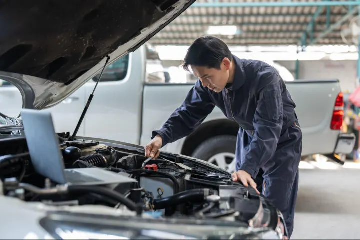 Professional mechanic cleaning and examining a vehicle’s engine area during Car BCM inspection and diagnostics