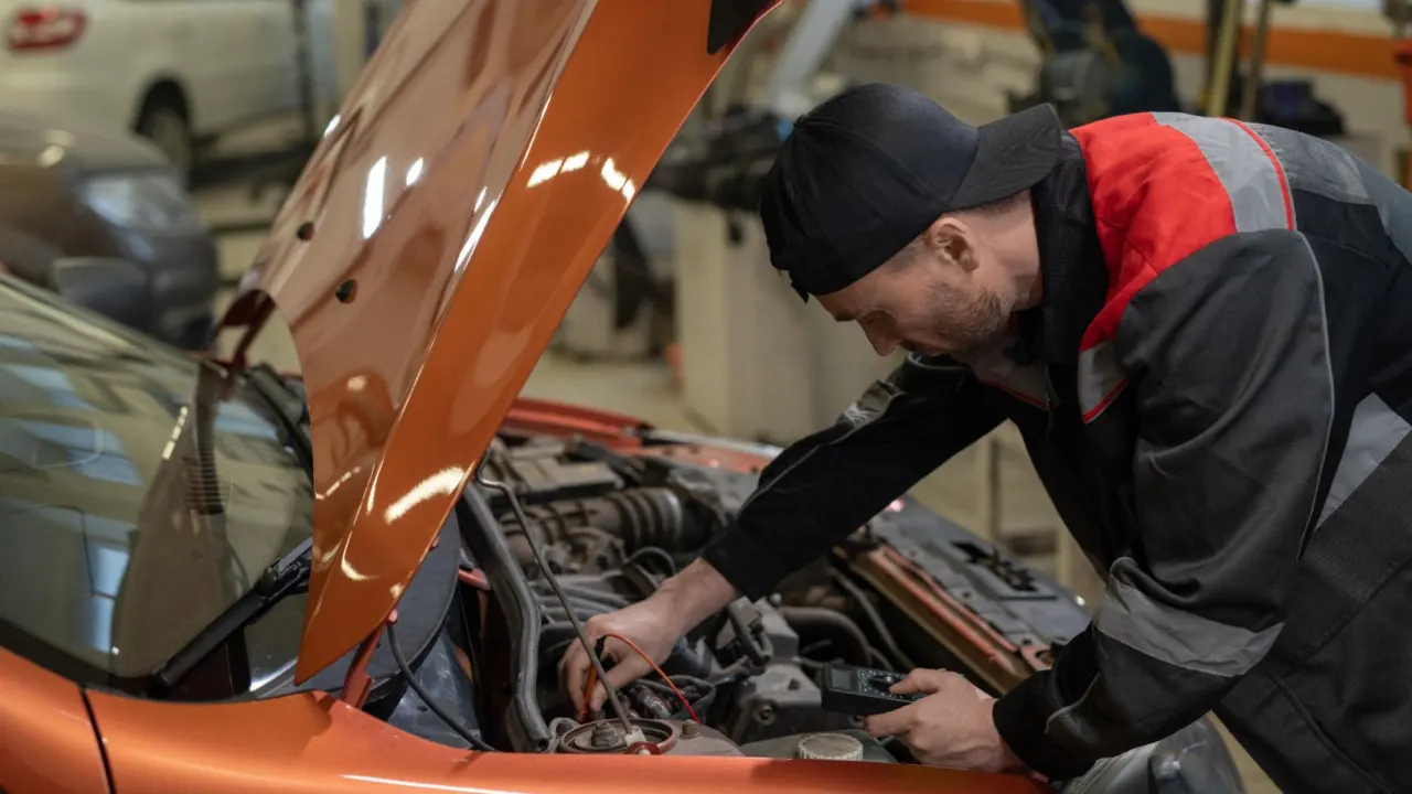 Young man checking vehicle engine components during ECM flash diagnostics.