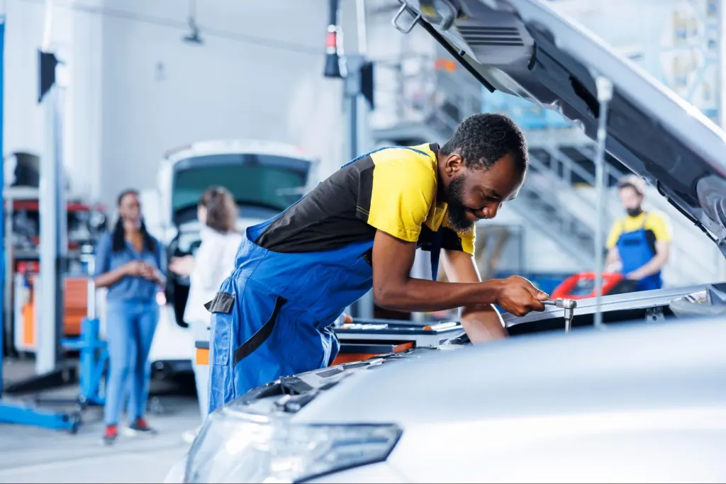Automotive technician inspecting under the hood to diagnose electrical and starting problems caused by a faulty Car BCM