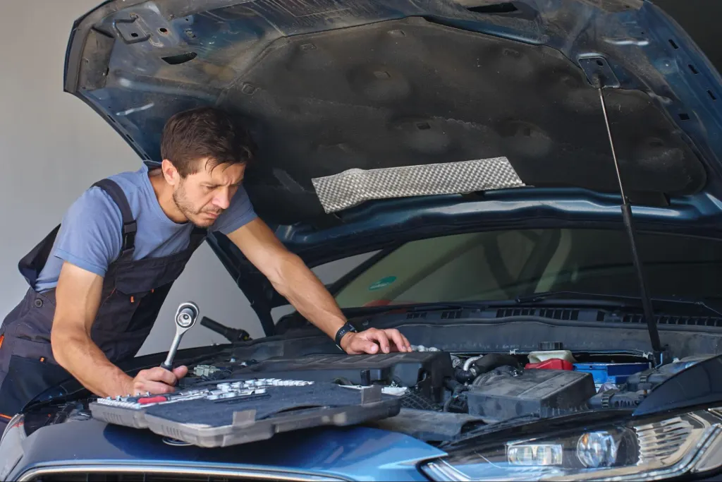 Auto technician performing testing of ECM inputs and outputs on a blue car to diagnose engine performance issues.
